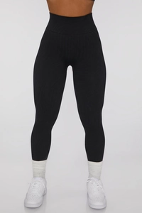 Detail of high-waist black yoga leggings with textured wave jacquard pattern and slimming fit
