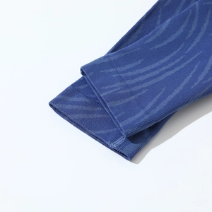 Detailed close-up of seamless dark blue knit fabric with subtle wavy pattern and ribbed cuffs