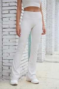 Detail showing high-elasticity cream ribbed knit fabric and flared hem of yoga pants