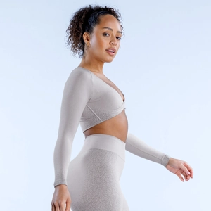 Detail of light beige seamless knitted yoga crop top showing deep V-neck and twist design