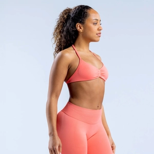 Detail view of coral pink halter sports bra and high-waisted leggings with ruched texture