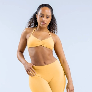 Detail of high-stretch yellow halter sports bra with ruched design and wide waistband