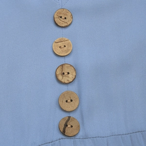 Macro detail of vertical wooden buttons on high-quality light blue twill fabric