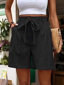 Detail of high waisted black shorts with a waist tie bow and side pockets for women
