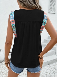 Detail of colorful crochet flower trim on the shoulder of a black sleeveless summer top