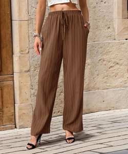 Close-up of brown pleated wide-leg trousers featuring elastic high waist and drawstring