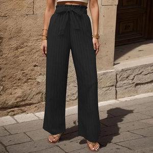 Dettaglio dei pantaloni neri a vita alta con cintura a fiocco e trama di tessuto a pieghe