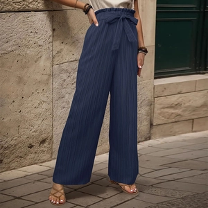 Dettaglio dei pantaloni larghi blu scuro a vita alta con texture a pieghe e cintura a fiocco