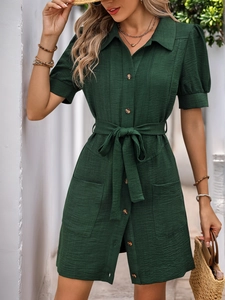 Detail of dark green textured shirt dress featuring amber buttons and a tie waist belt
