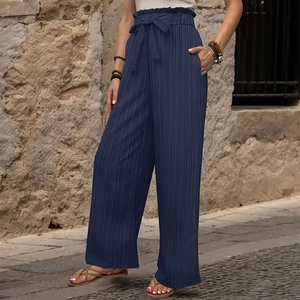Dettaglio dei pantaloni blu scuro a gamba larga con vita paperbag e tessuto testurizzato