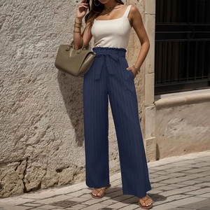 Dettaglio dei pantaloni plissettati blu navy a vita alta con cintura e bordo a sacchetto