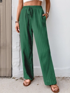 Detail of high waist drawstring on dark green pleated wide leg trousers with pockets