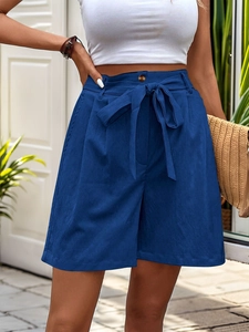 Close-up of navy high-waisted shorts with bow tie belt and textured cotton linen fabric