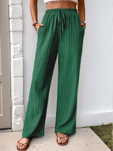 Close-up of forest green high-waisted wide-leg pants with pleated texture and drawstring