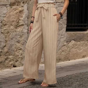 Dettaglio dei pantaloni a vita alta plissettati a gamba larga con fiocco in beige