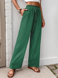 Detail view of emerald green high-waisted wide-leg pants featuring fine pleated texture