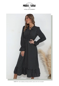 Close-up of V-neck tie-up detail and white polka dot print on black long-sleeve dress
