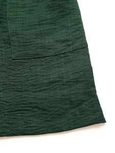 Detailed macro view of dark green textured fabric with pocket seam and hem stitching