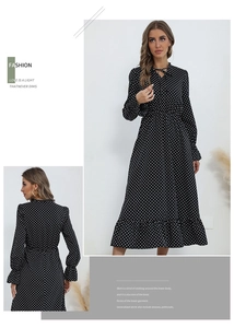 Detail of white polka dot dress with tie V-neck and ruffled hem on white background