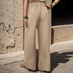 Dettaglio dei pantaloni a gamba larga plissettati a vita alta con elastico e trama fine