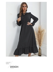 Close-up of the black polka dot dress featuring a V-neck tie and ruffled hem details