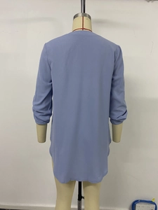 Detail view of the side split and irregular hem on light blue long sleeve chiffon top