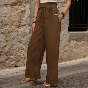 Dettaglio dei pantaloni plissettati a vita alta con cintura a fiocco e gamba larga