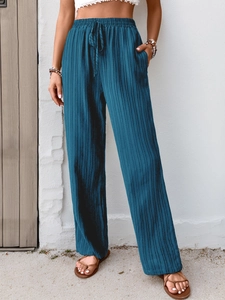 Close-up of dark blue pleated wide-leg pants with elastic drawstring waist and side pockets