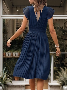 Detail of navy blue pleated midi dress featuring ruffled cap sleeves and back tie design