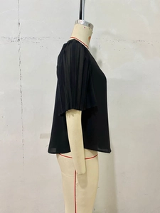 Detail view of black blouse featuring pleated puff sleeves and semi-sheer chiffon fabric