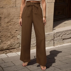 Dettaglio vita paperbag con fiocco e trama a pieghe sui pantaloni marroni a gamba larga