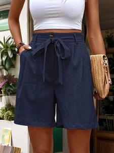 Close-up of navy blue paper-bag waist shorts featuring a stylish tie-knot bow and pleat detail