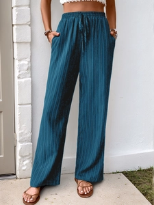 Detail of navy pleated fabric texture and elastic drawstring waist on wide-leg trousers