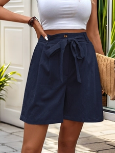 Detail of navy blue high-waisted shorts with a bow belt and amber button closure