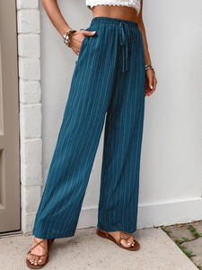 Detail of high waist elastic waistband with drawstring on pleated wide-leg navy trousers