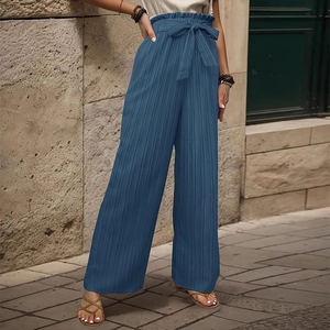 Dettaglio dei pantaloni plissettati blu navy a gamba larga con fiocco a vita alta