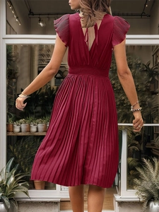 Detail of wine red pleated dress featuring elegant ruffled sleeves and backless V-neck design