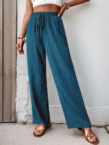 Detail of high waist wide leg pants showing navy blue pleated texture and drawstring waist