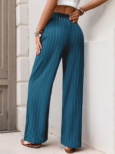 Detailed back view of high-waist pleated wide-leg trousers in vibrant lake blue fabric