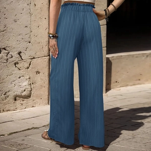 Dettaglio dei pantaloni plissettati blu a vita alta con eleganti finiture a balze in vita