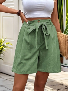 Detail view of grass green high-waisted shorts with a matching bow belt and pleated waist