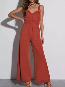 Detailed view of rust red wide-leg jumpsuit with spaghetti straps and pleated waist