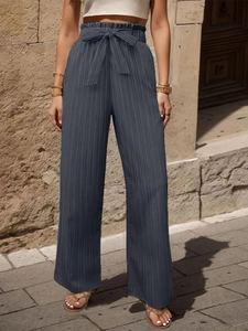 Dettaglio di pantaloni plissettati a gamba larga a vita alta con cintura a fiocco chic