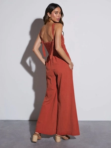 Detail of cross-back bow straps on a brick red linen high waist wide leg jumpsuit