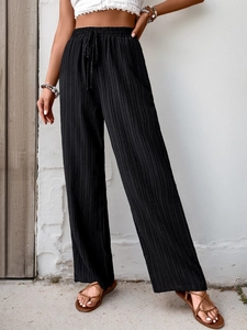 Detail of high waisted black wide leg trousers featuring pleated fabric and elastic drawstring