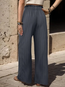 Dettaglio dei pantaloni a gamba larga plissettati grigio scuro con vita elastica