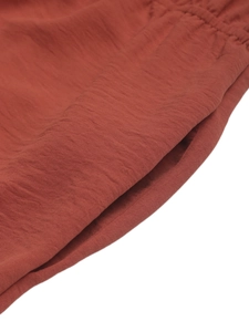 Detail view showing breathable smocked texture and side pocket of the red jumpsuit