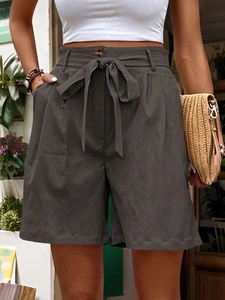 Close-up of high-waisted shorts featuring a fabric bow belt and side slanted pockets