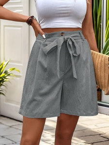 Macro shot of high-waist grey shorts featuring a fabric tie belt and vintage brown button