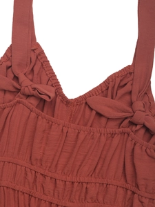 Detailed macro view of the rust red neckline with spaghetti straps and bows